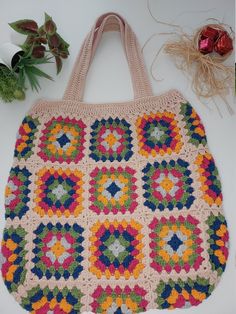 a crocheted bag sitting on top of a table next to some flowers and yarn