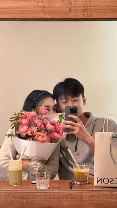 a man and woman taking a selfie in front of a mirror with flowers on it