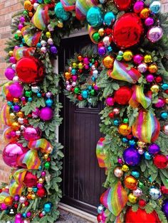 a christmas wreath with colorful ornaments hanging on the front door and behind it is a brick wall