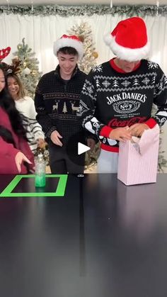 a group of people standing around a table in front of a christmas tree with presents