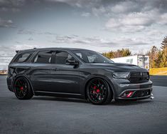 the grey dodge duran is parked in an empty parking lot with dark clouds above it