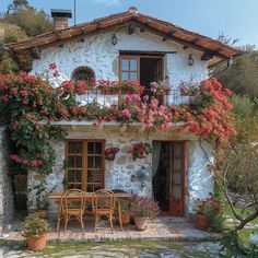 an old stone house with flowers growing on it