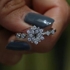 a woman's hand holding a ring with an intricate design on the middle finger