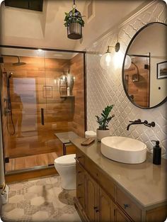 a bathroom with a sink, toilet and shower stall in the background is a large mirror