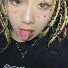 a woman with long blonde hair sticking her tongue out and wearing tattoos on her face