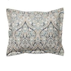 a blue and white pillow with an ornate design on the front, sitting against a white background