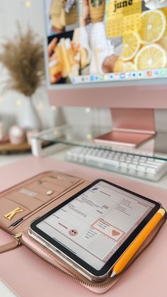 a tablet sitting on top of a pink desk next to a computer monitor and keyboard