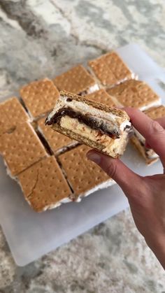 a person holding up a sandwich in front of some crackers