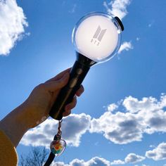 a person holding a light up in the air with clouds behind them and blue sky