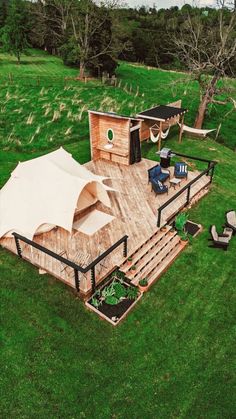 an aerial view of a wooden deck in the middle of a grassy area with chairs and umbrellas