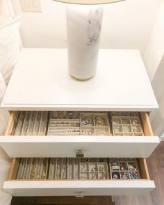 a white table topped with drawers filled with books and magazines on top of a hard wood floor