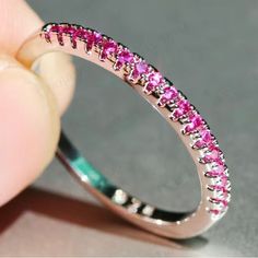 a pink diamond ring is being held up by someone's hand with their finger