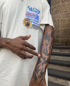 a man with tattoos on his arm pointing at something