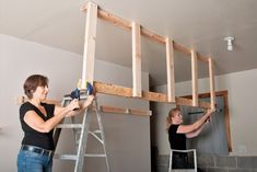 two women are working on an unfinished wall in a room that is being built into the ceiling