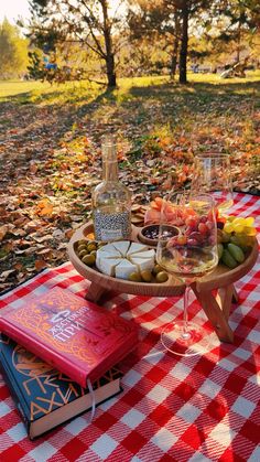 an outdoor picnic with food and drinks on the table in the fall leaves, surrounded by trees