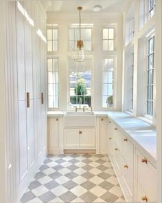 a white kitchen with checkered flooring and cabinets in the corner, along with two windows