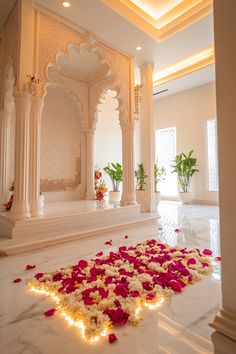 a white room with flowers on the floor and lights in the middle, surrounded by pillars