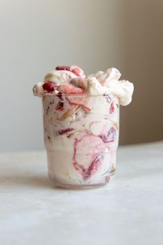 a cup filled with whipped cream and cranberries on top of a white counter