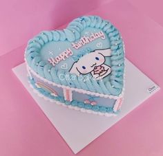 a heart shaped birthday cake with an image of a cat on it's side