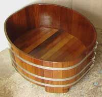 a wooden barrel shaped sink sitting on top of a stone floor next to a wall