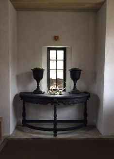 a table with two vases on it in front of a window