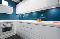 a kitchen with blue walls and white cabinets, an oven and countertop space in the middle