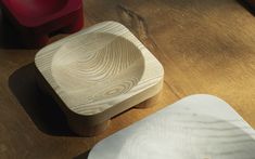 two wooden bowls sitting next to each other on top of a wooden table with red chairs in the background