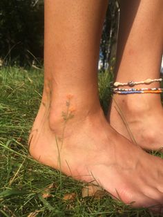 two people standing in the grass with their bare feet covered by bracelets and flowers