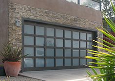 a garage door is shown in front of a house with plants and potted grass