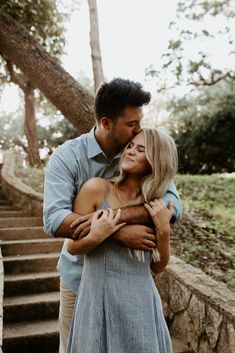 a man and woman embracing each other in front of some stairs