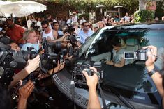 a group of people standing around a car with cameras on the front and back seats