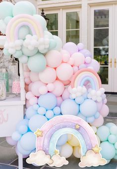 a bunch of balloons that are in the shape of rainbows and clouds on a table