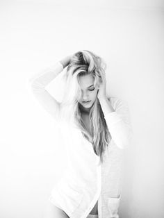 black and white photograph of a woman holding her hair in front of her head with both hands