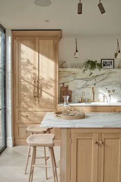 a kitchen with marble counter tops and wooden cabinets, two stools in front of the sink