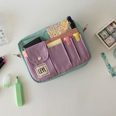 the contents of a purse are laid out on a white table with pens, scissors and other items