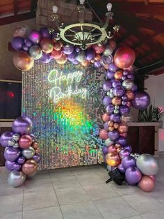 an arch made out of balloons with the words happy birthday written on it in front of a wall