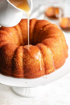 a bundt cake is being drizzled with caramel sauce on a white plate