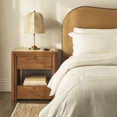 a bed with white sheets and pillows in a bedroom