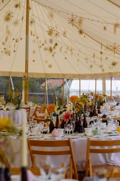 the inside of a tent with tables and chairs set up for a formal dinner party