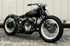 a black and white motorcycle parked in front of a garage door on a brick sidewalk