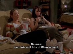 two women sitting on a couch eating food and drinking beverages in front of them with the caption, no men just lots and lots of chinese food