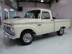 an old white pickup truck parked in a garage