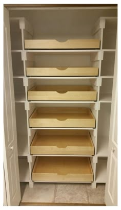 an empty closet with white shelves and wooden bins on the bottom shelf, along with tile flooring