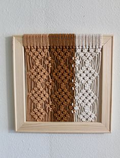 three different colors of crochet are hanging on the wall in front of a wooden frame