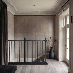 an empty room with a railing and vase on the floor