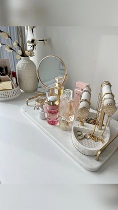 a white counter topped with lots of different types of cosmetics and perfume bottles on top of it