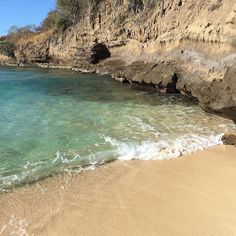 the water is crystal blue and clear at this beach near some rocky cliff formations,