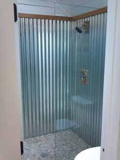 a glass shower door in a bathroom next to a toilet