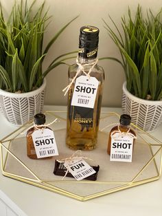 three bottles of whiskey sitting on top of a table next to potted plants and tags