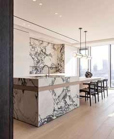 a kitchen with marble counter tops and an island in front of a large glass window